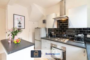 a kitchen with white cabinets and a black tile wall at The Hyde Away Chic Urban Two Bedroom House By Movida Property Group Short Lets & Serviced Accommodation in Headingley