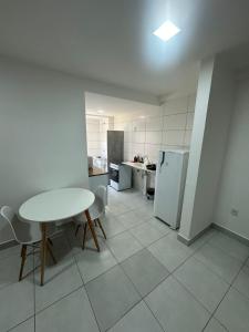 a white kitchen with a table and a refrigerator at Apartamento 2 quartos in Goiânia