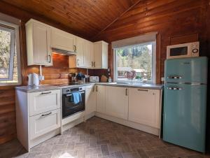 a kitchen with white cabinets and a blue refrigerator at Ruskin Lodges Argyll, by Puck's Glen, Rashfield near Dunoon in Dunoon