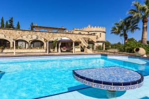 una piscina frente a un edificio con palmeras en Castell Bohio, en Urbanización Ses Palmeres