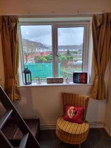 a chair with a pillow sitting in front of a window at Apartment 9 3/4 in Watford