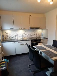 a kitchen with white cabinets and a sink and a table at Am-Deichtor in Dornumersiel