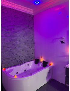a white bath tub in a room with purple lights at Belle Appartement avec Jaccuzzi à Diamniadio in Dakar