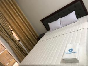 1 dormitorio con cama blanca y ventana en Hotel Nam Sơn Tân Dương, en Chơ Mơi