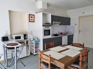 une cuisine avec une table en bois, une table et des chaises dans l'établissement Spacieux Appartement RDC tout confort, à Lorient