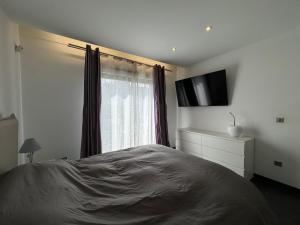 um quarto com uma cama, uma televisão e uma janela em Villa Benouville em Bénouville