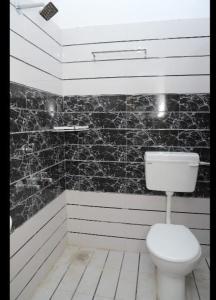 a bathroom with a white toilet and black tiles at HOTEL PARADISE INN in Shinaya