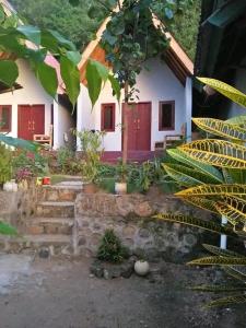 una casa con puertas rojas y escaleras delante en Putri Nyale Bungalow, en Kuta Lombok