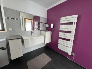 uma casa de banho com um lavatório e uma parede roxa em Villa Benouville em Bénouville
