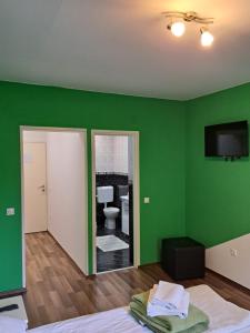 a green room with a bed and a toilet at Rooms Modrušan in Slunj