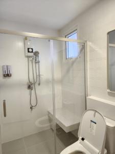 a white bathroom with a shower and a toilet at NARAH in Ban Thap Nang
