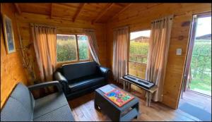 una sala de estar con sofá y mesa en una cabaña en CABAÑAS VILLA INES DE SUESCA en Suesca