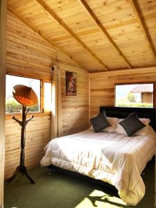 una camera con un letto in una cabina di legno di CABAÑAS VILLA INES DE SUESCA a Suesca