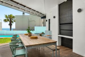 a dining room with a wooden table and chairs at Neighbourgood 1st Crescent Camps Bay in Cape Town