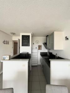 a kitchen with white cabinets and a black counter top at Appartement devant la mer + parking in Le Grau-du-Roi