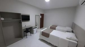 a white bedroom with a bed and a desk at NOVO HOTEL in Conceição do Coité