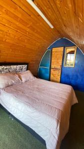 un grande letto in una camera con soffitto in legno di CABAÑAS VILLA INES DE SUESCA a Suesca