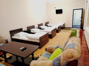 una habitación con una fila de camas y una mesa en ZARIN Guest House B&B, en Bukhara