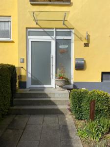 uma porta branca num edifício amarelo com escadas em Ferienwohnungen Pohl em Bad Rodach
