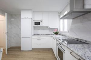 eine weiße Küche mit weißen Schränken und einem Waschbecken in der Unterkunft Alhóndiga Flat by Next Stop Bilbao in Bilbao