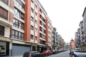 eine Stadtstraße mit Autos, die vor den Gebäuden geparkt sind in der Unterkunft Alhóndiga Flat by Next Stop Bilbao in Bilbao