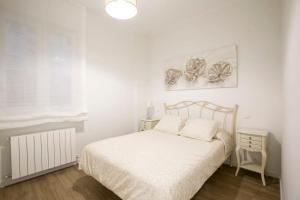 a white bedroom with a bed and a lamp at Alhóndiga Flat by Next Stop Bilbao in Bilbao