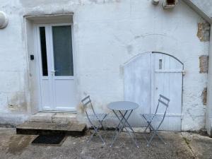 2 chaises et une table devant une porte dans l'établissement Studio en rez-de-chaussée avec cour dans le centre de Vendome, à Vendôme