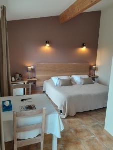 een slaapkamer met een bed, een tafel en een bureau bij Côté Lavande in Crestet