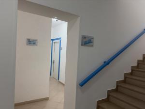 a hallway with stairs and a blue stair railing at Garden Hotel Alghero in Fertilia