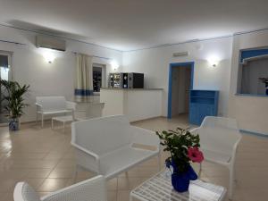 a living room with white chairs and a vase of flowers at Garden Hotel Alghero in Fertilia