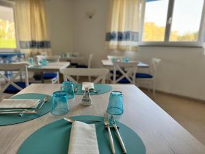 a dining room with blue plates and silverware on a table at Garden Hotel Alghero in Fertilia