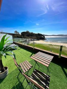 卡馬里納斯的住宿－Playa de Camariñas，草坪上的木凳和椅子,带海滩