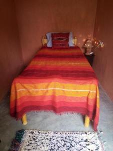 ein Schlafzimmer mit einem Bett mit einer roten und gelben Decke in der Unterkunft Ecolodge du Draa in Ouled Otmane
