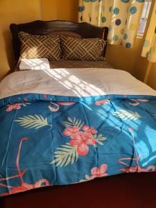 uma cama com um cobertor azul com flores em MAGGY LODGE em Kagio
