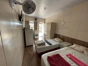 a small room with two beds and a refrigerator at Hospedaria cmc unidade 05 com estacionamento in Brasilia
