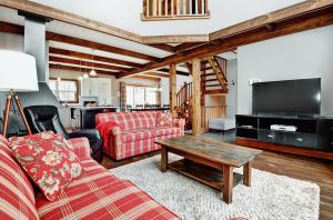 a living room with a couch and a tv at Chalet 9010 Chemin des Alpages by Les Chalets Alpins in Stoneham