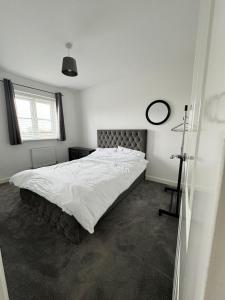 um quarto com uma cama grande e lençóis brancos em The willows em Hardingstone