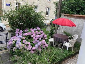 a table with a red umbrella and purple flowers at Villanelle maison en centre hyper calme et au vert in Limoges