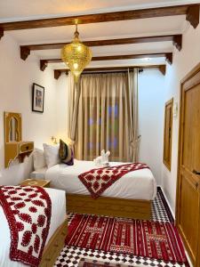 a bedroom with two beds and a chandelier at Dar MD in Chefchaouene