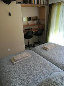 two beds in a bedroom with two chairs and a desk at Le ti'Roussat in Saint-André-de-Cubzac