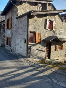 an old stone house with wooden doors on a street at La casetta di campagna in Mazzo di Valtellina