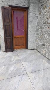 a wooden door in a building with a stone wall at La casetta di campagna in Mazzo di Valtellina