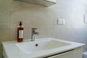 a bathroom with a sink with a bottle on it at Yourbanflat Manga in Padova +12 photos