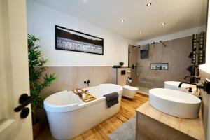 a bathroom with two sinks and a tub and two toilets at EDLER WOHNRAUM Einmalige 140 qm mit Kamin, Klimaanlage, Kaffeevollautomat, Netflix, 2 Balkonen & 2 Tiefgaragenplätzen in Chemnitz