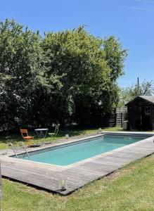 ein Schwimmbad mit einem Holzweg um ihn herum in der Unterkunft Maison de charme avec piscine in Vignoux-sous-les-Aix