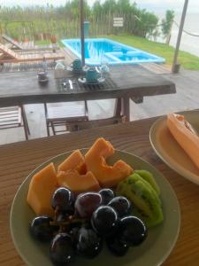 a plate of fruit on a table near a pool at Delta Chalé in Tutóia