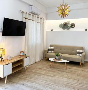a living room with a couch and a tv on a wall at "Calm Joy & J" - Family in Ermoupoli