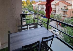 a table on a balcony with a view of a street at Appartement cosy et lumineux à St Estève avec belle vue in Saint-Estève
