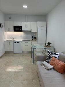 eine Küche und ein Wohnzimmer mit einem Sofa und einem Tisch in der Unterkunft House Isleta Dream in Las Palmas de Gran Canaria