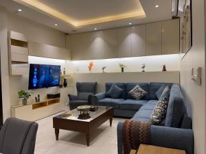 sala de estar con sofá azul y TV en شقق خاصه بطابع حديث وفندقي - تسجيل ذاتي Private apartments with modern vibes - self checkin, en Riad